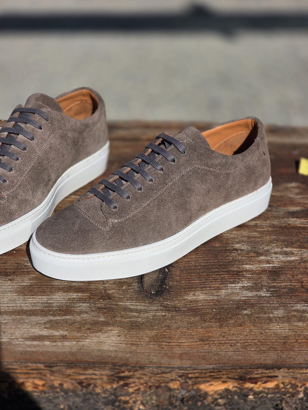 A pair of gray suede sneakers with white soles and dark gray laces.