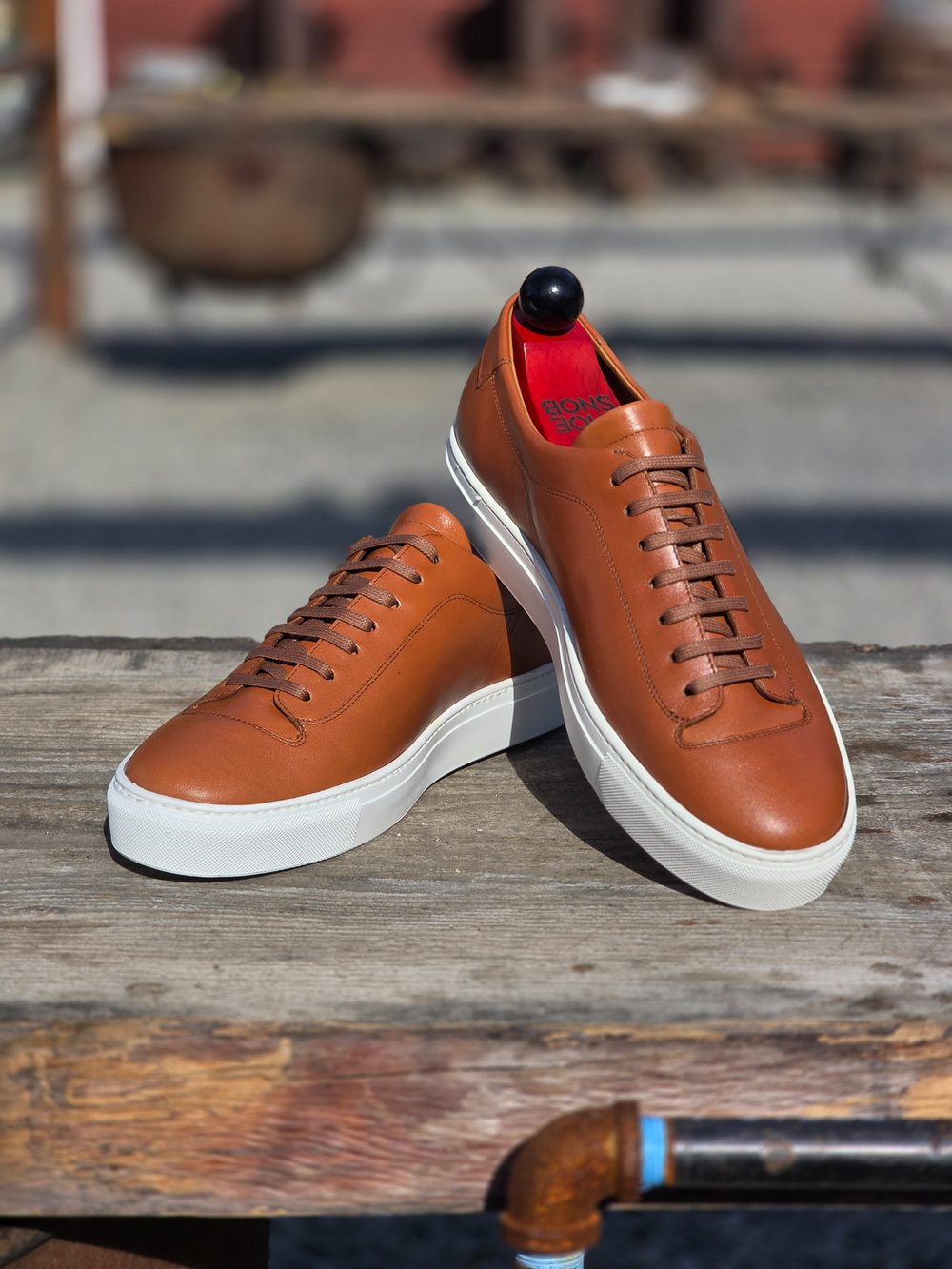 Brown leather sneakers with white soles and red insoles.