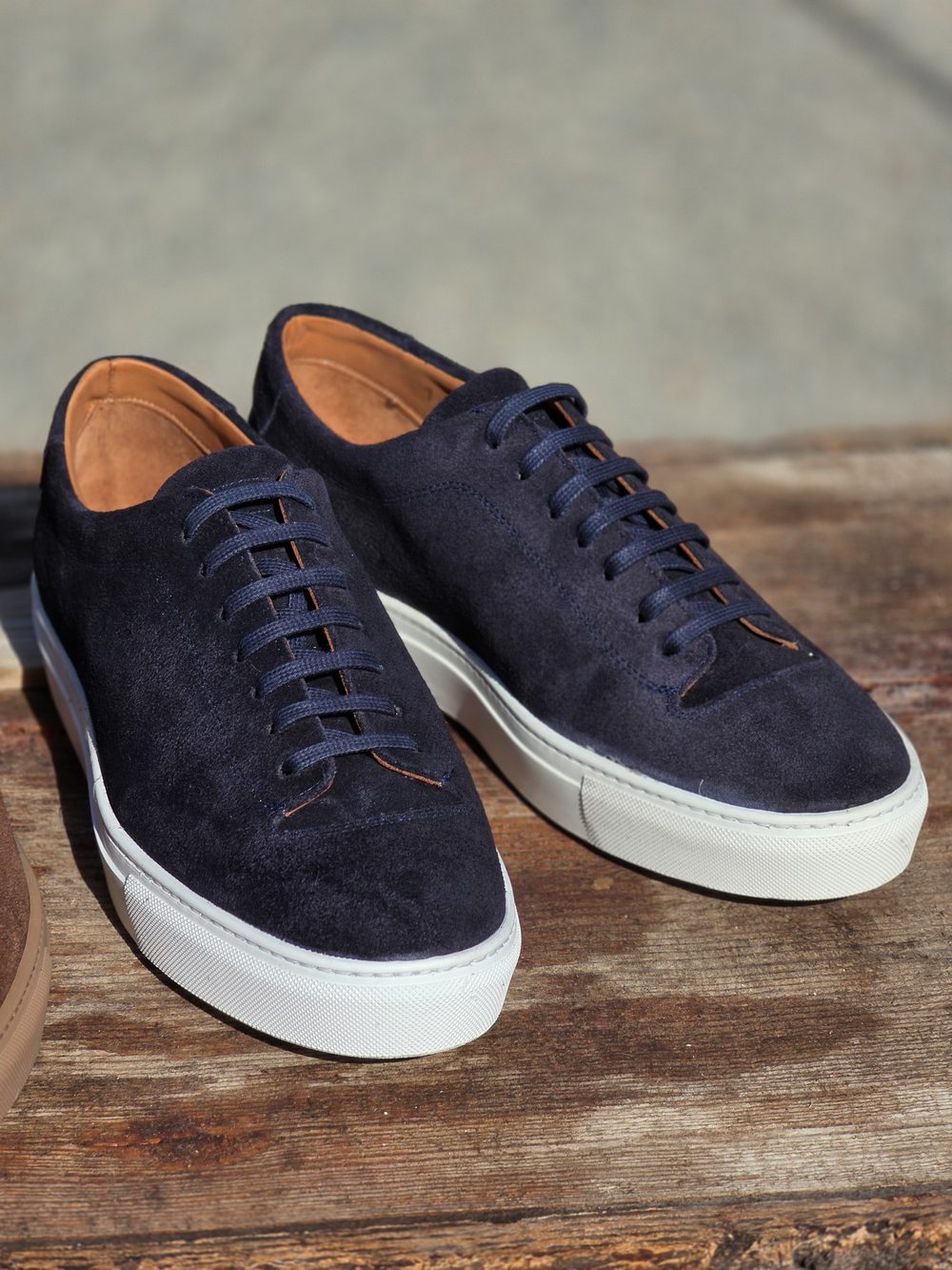 A pair of navy suede sneakers with white soles and dark laces.