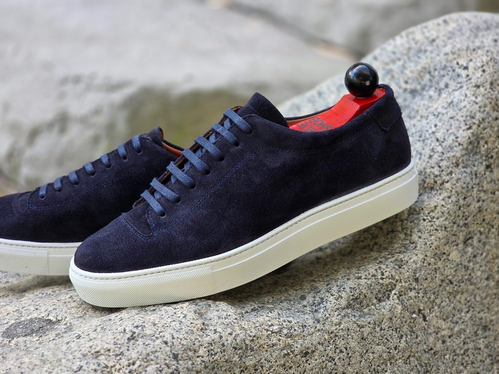 Navy suede sneaker with a white sole and red interior details.