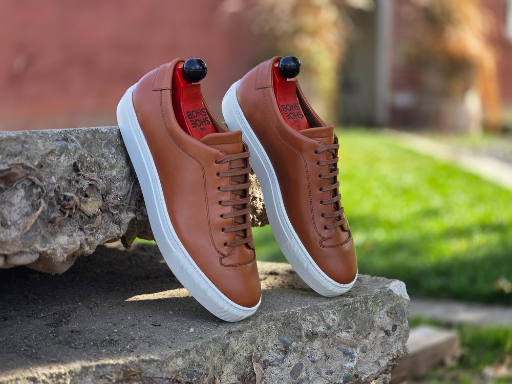 Brown leather sneakers with white soles, featuring red insoles and black heel caps.