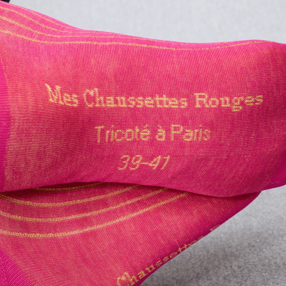 Close-up of pink socks with gold text reading "Mes Chaussettes Rouges, Tricoté à Paris, 39-41," illustrating the style in the over the calf vs mid calf socks comparison.
