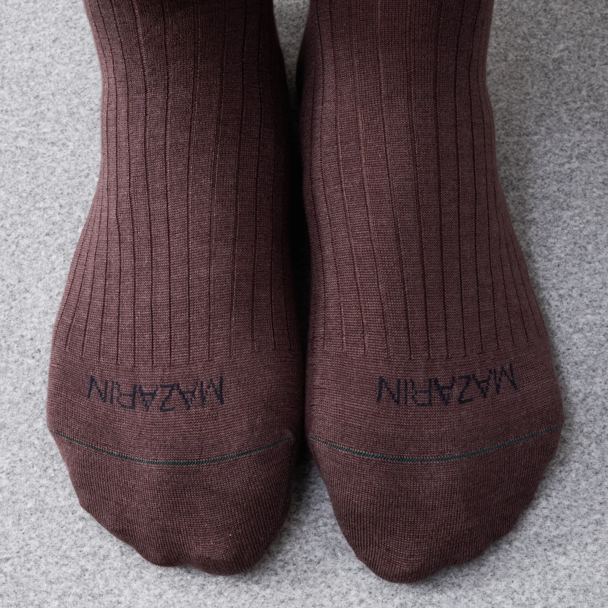 Two brown ribbed socks with a brand label, illustrating the topic of over the calf vs mid calf socks.