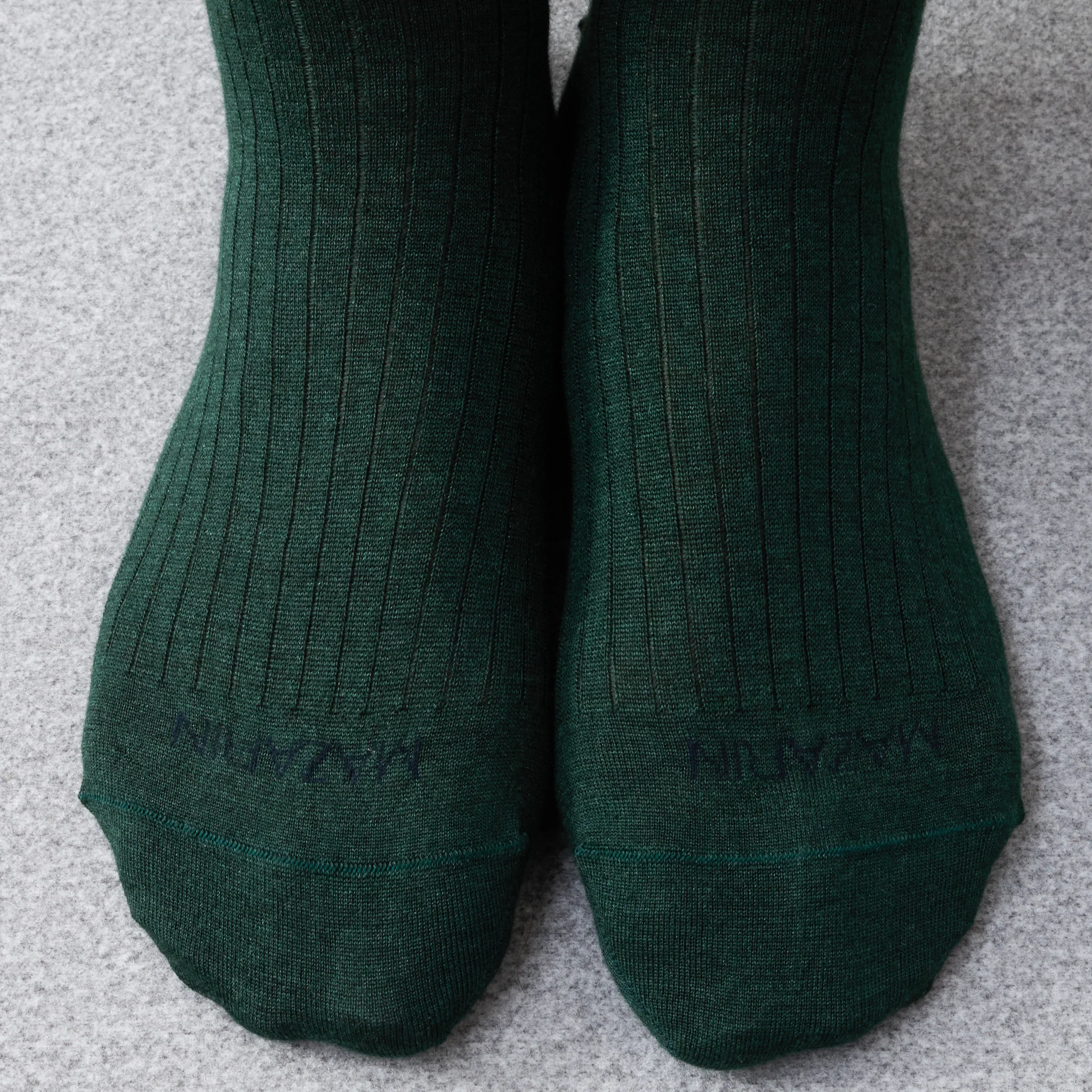 Two pairs of dark green ribbed socks, illustrating the comparison of over the calf vs mid calf socks.