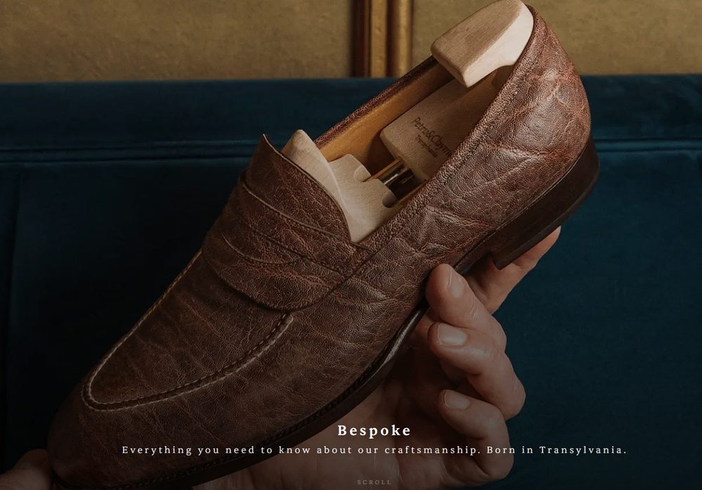 A hand holds a brown leather shoe with a wooden shoe tree inside.