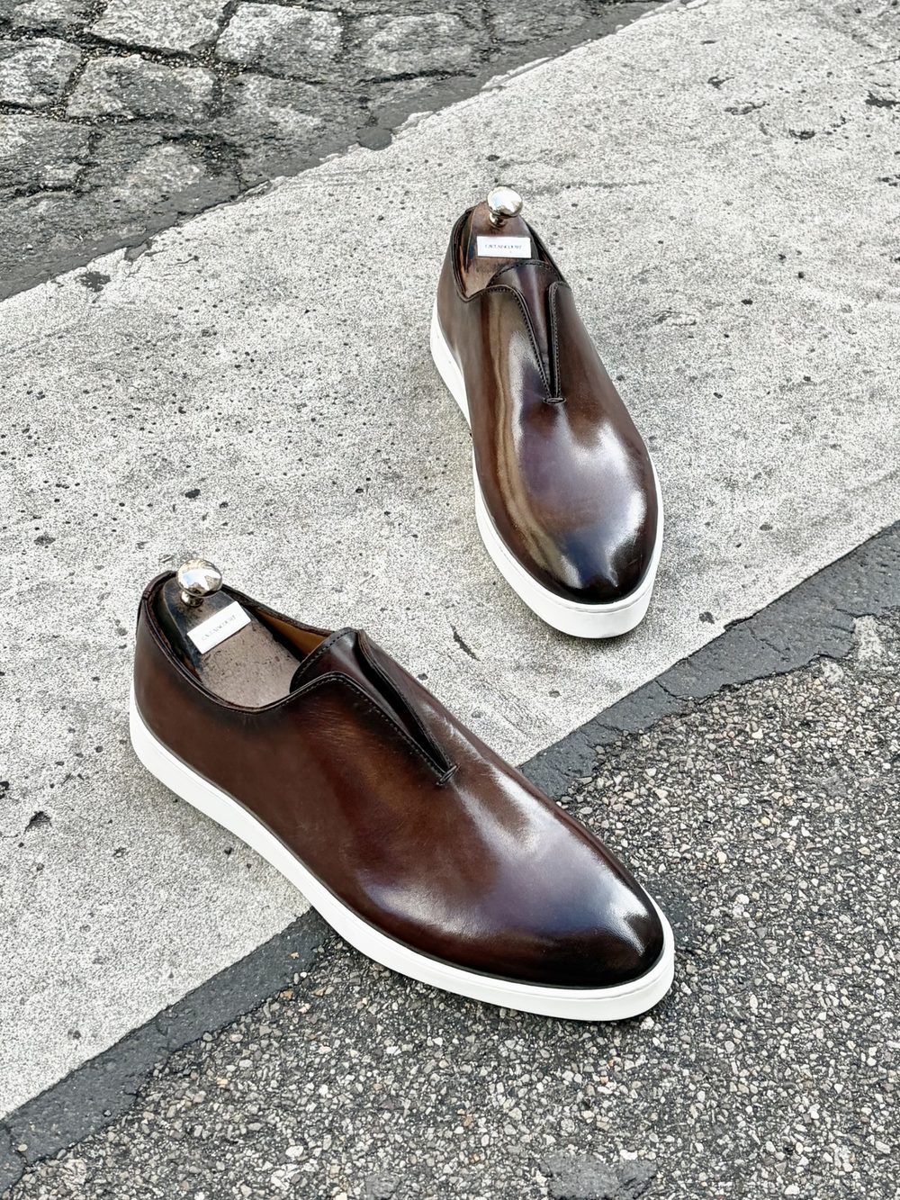 Brown leather sartorial sneakers with white soles and a sleek design.