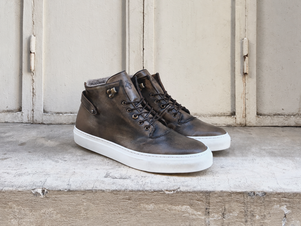 Brown leather high-top sneakers with a white sole and decorative side buttons.