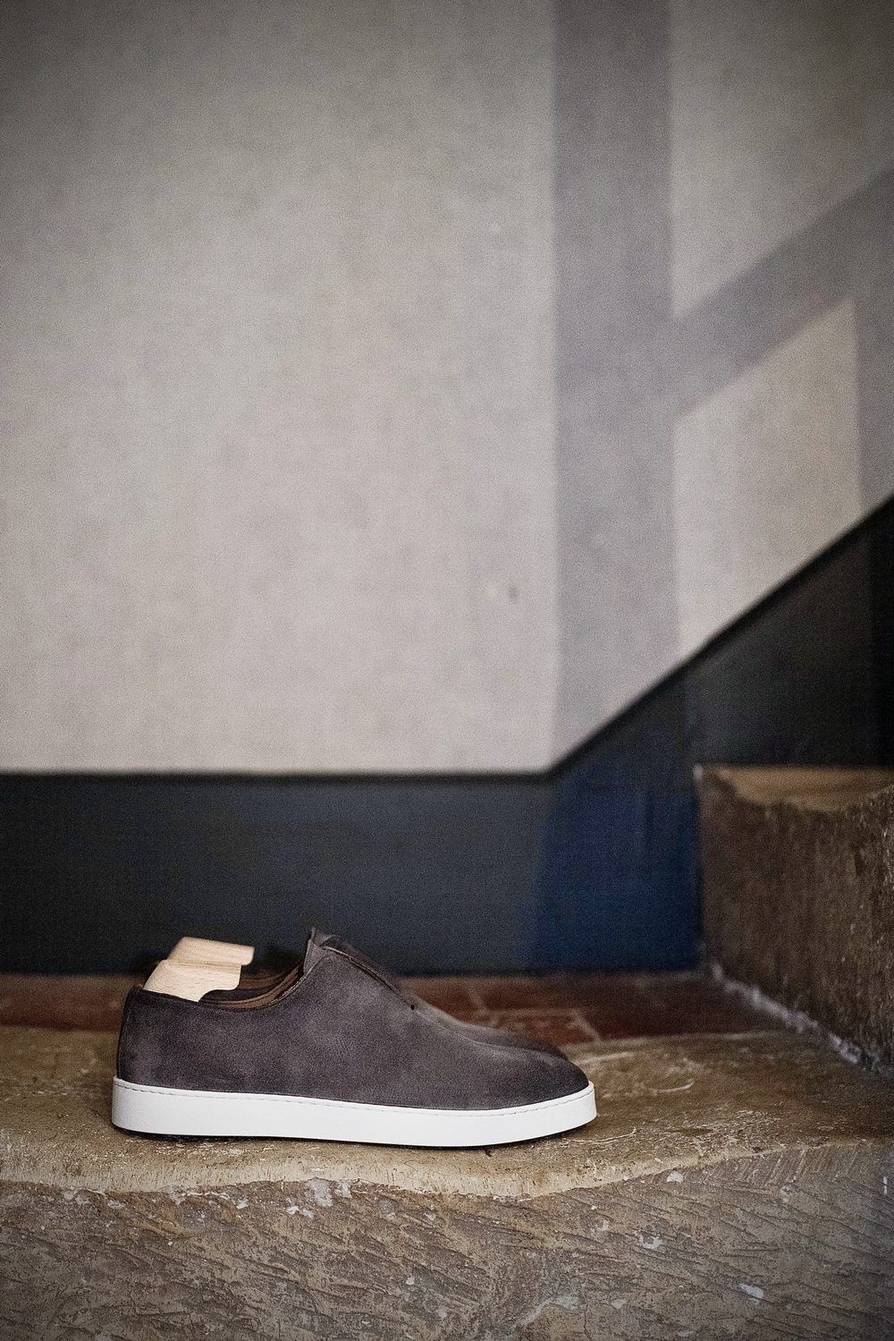 A stylish gray suede sneaker with a white sole and a wooden heel detail.
