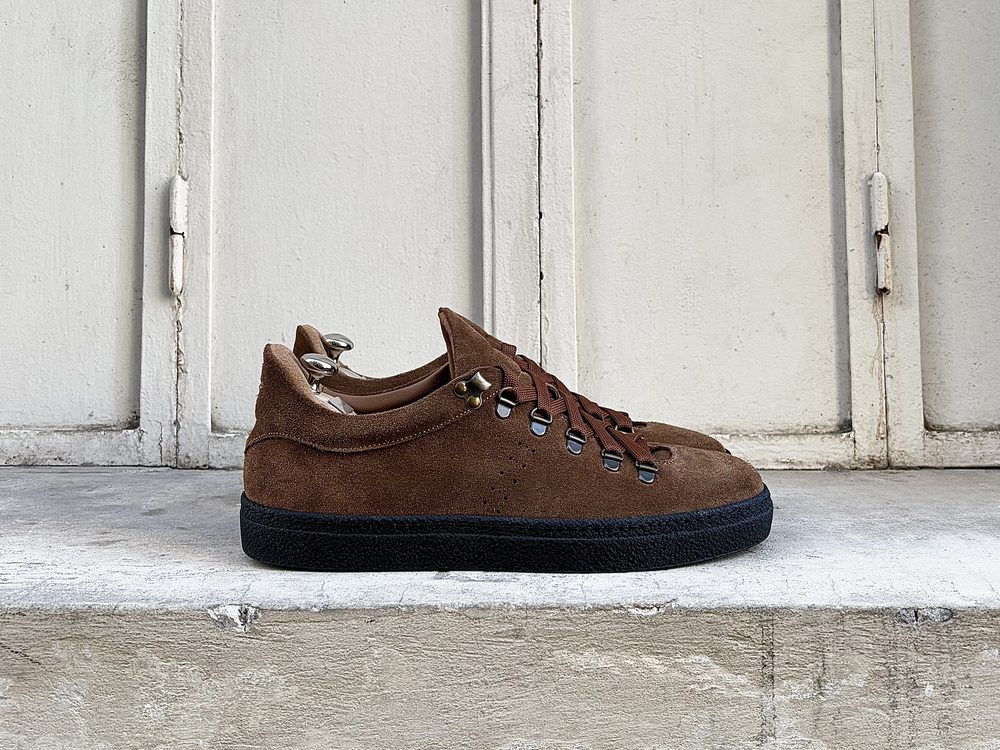 Brown suede sneakers with black soles and metal eyelets.