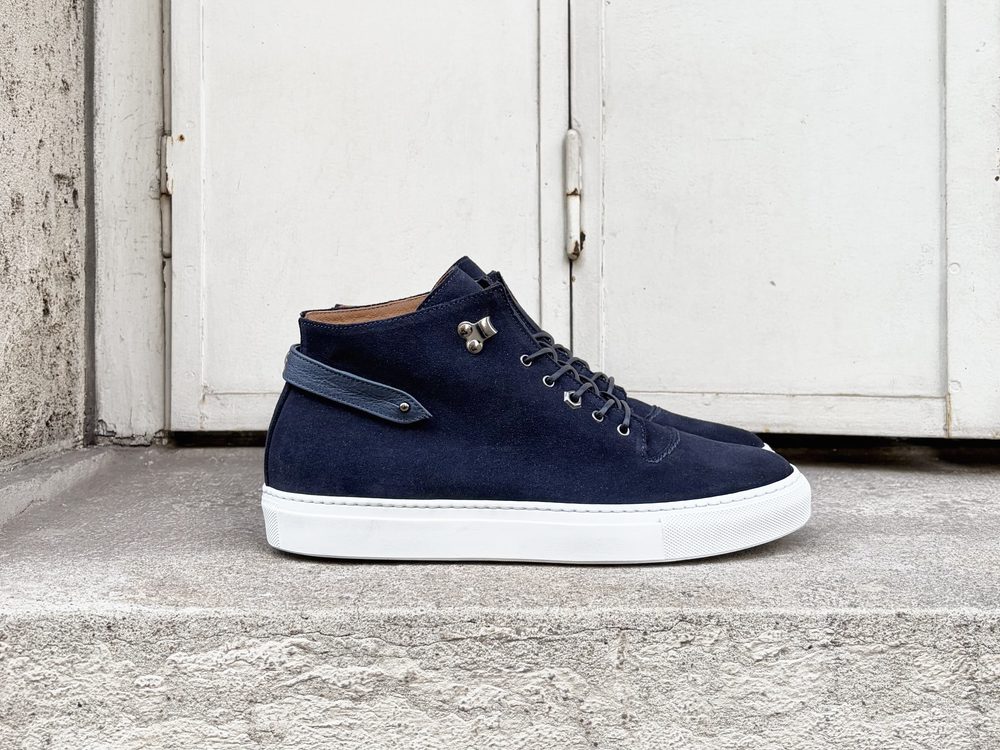 A navy blue suede high-top sneaker with a white sole and leather details.