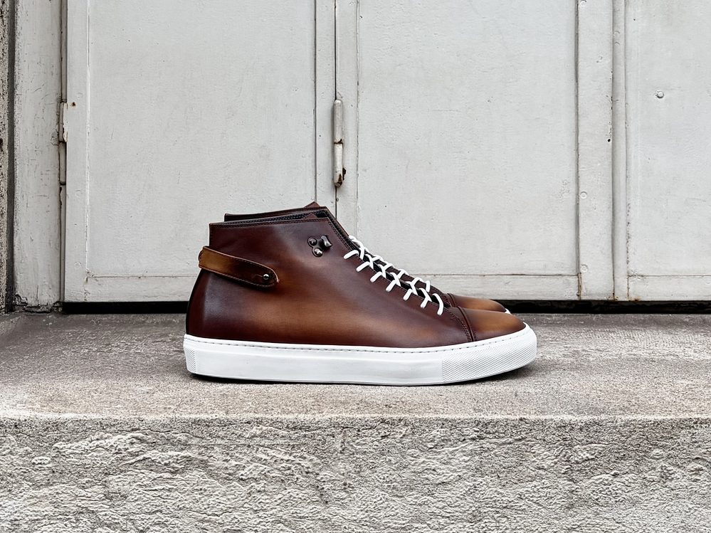 A pair of brown leather high-top sneakers with a white sole and laces.