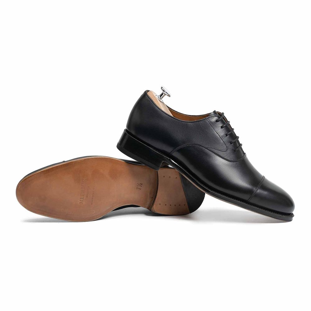 A pair of black leather dress shoes with a polished finish and a visible shoehorn.