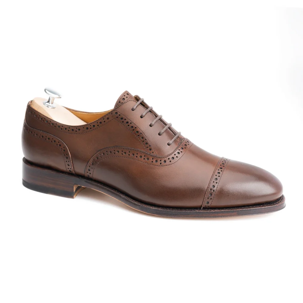 Brown leather dress shoe with decorative perforations and a polished cap toe.