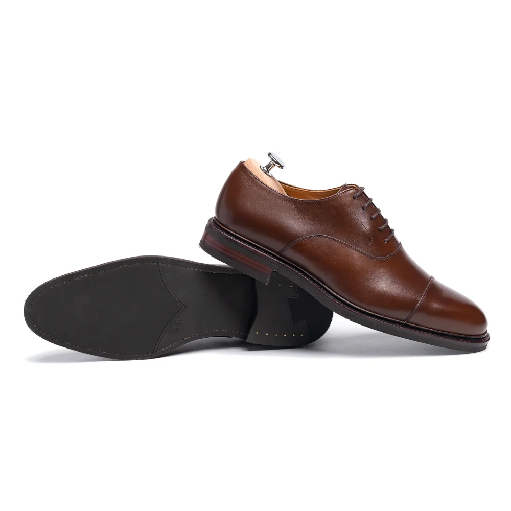 A pair of brown leather dress shoes with a sleek design and a rubber sole.