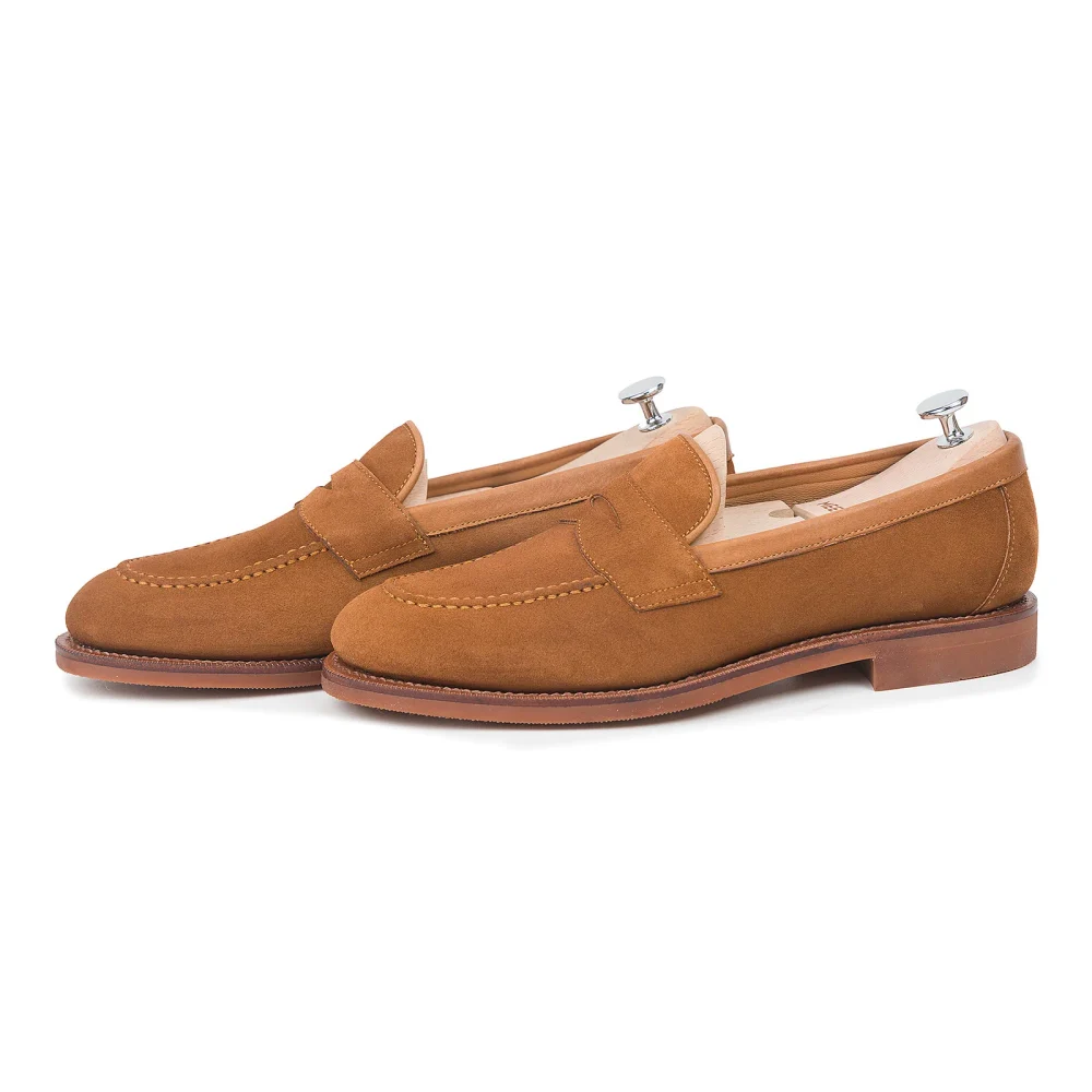 A pair of brown suede loafers with leather accents.