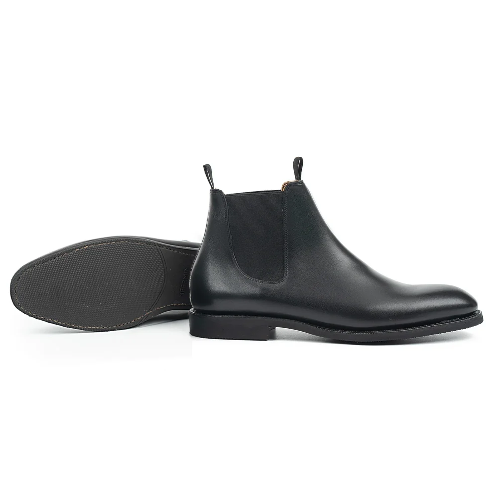 Black leather Chelsea boots with elastic side panels and flat soles.