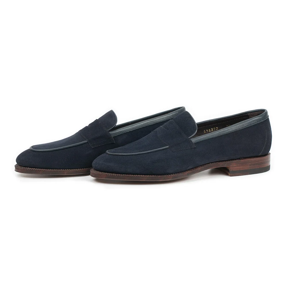 Navy blue suede loafers with a brown leather sole.