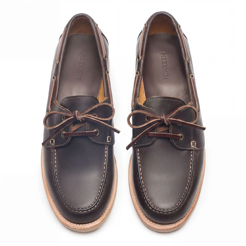 A pair of dark brown leather shoes with a smooth finish, featuring brown laces and a light-colored sole.