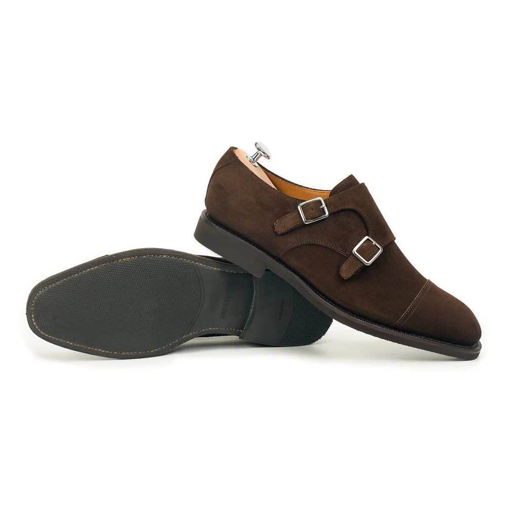 Brown suede double monk strap shoes with silver buckles and a black rubber sole.