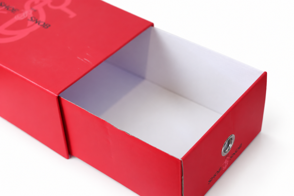 A red shoe box with a white interior, featuring a circular metal eyelet, relevant to the shoe care guide.