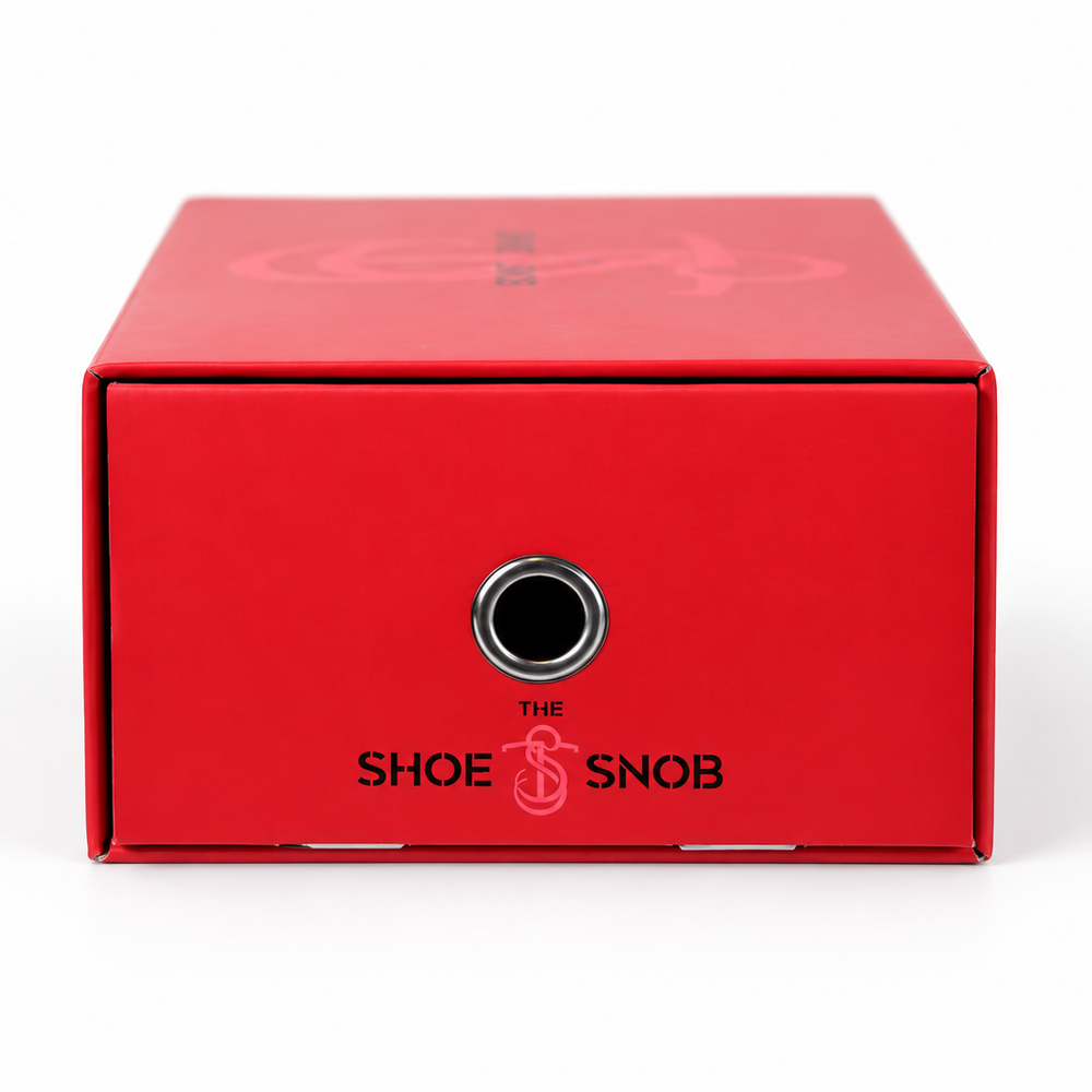 A red shoe box labeled "The Shoe Snob," featuring a circular hole for ventilation.