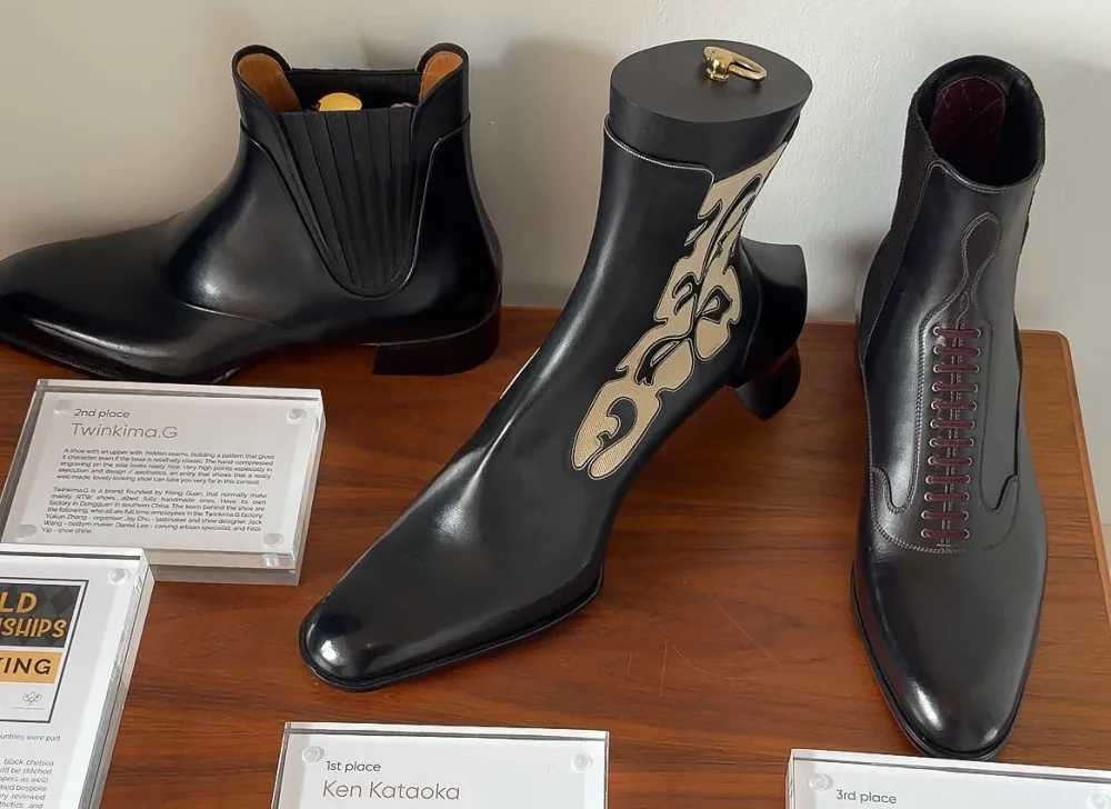 Three pairs of artistic black leather boots displayed on a table, featuring unique designs and finishes.