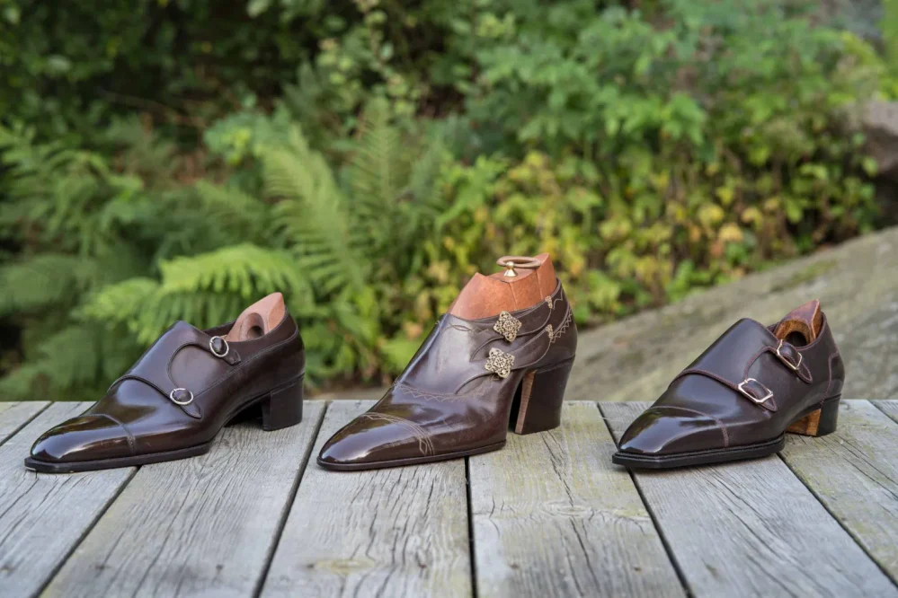 Three pairs of elegant brown leather shoes with pointed toes and varying designs, showcased on a wooden surface.