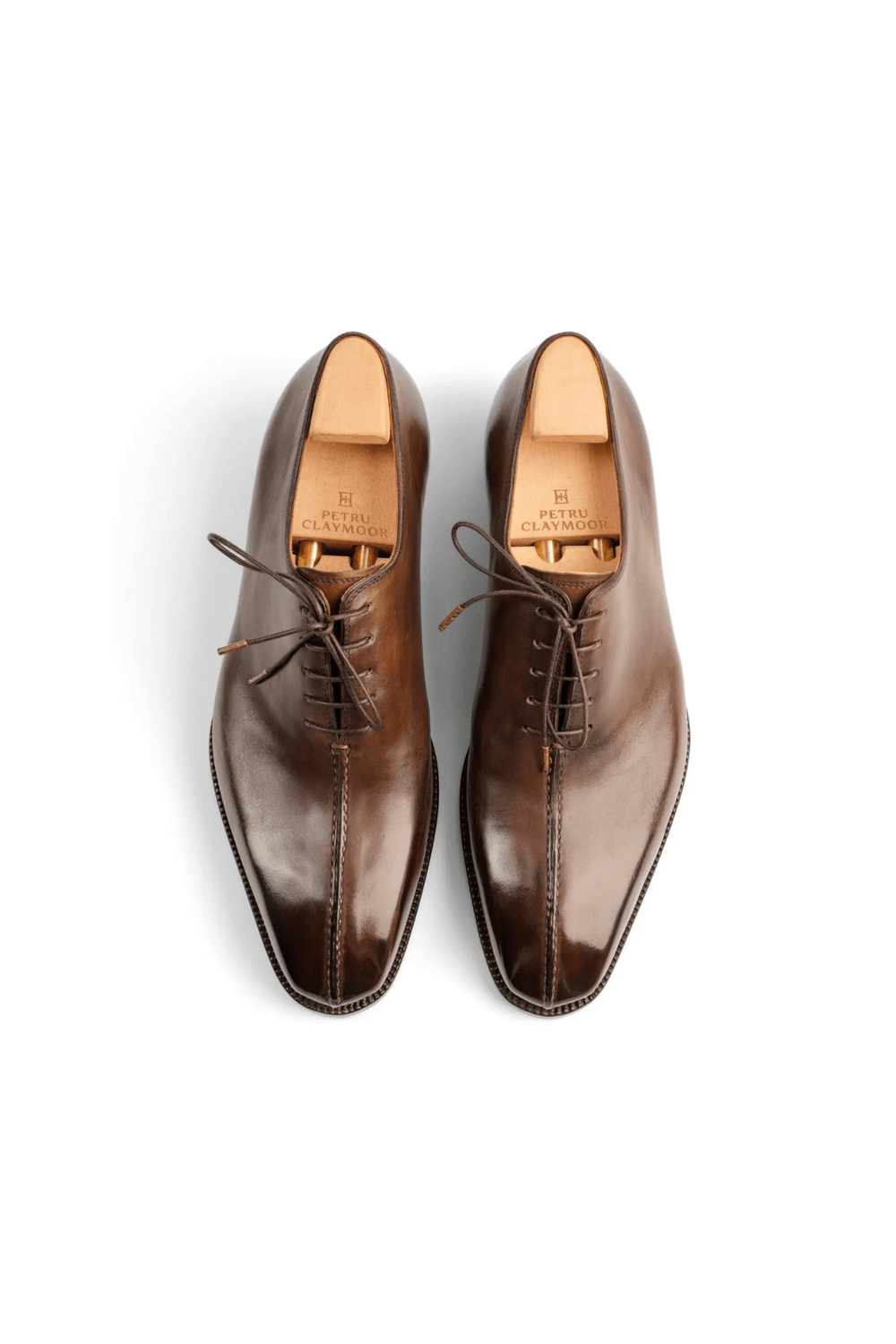 A pair of polished brown leather shoes with laces, featuring a pointed toe design.