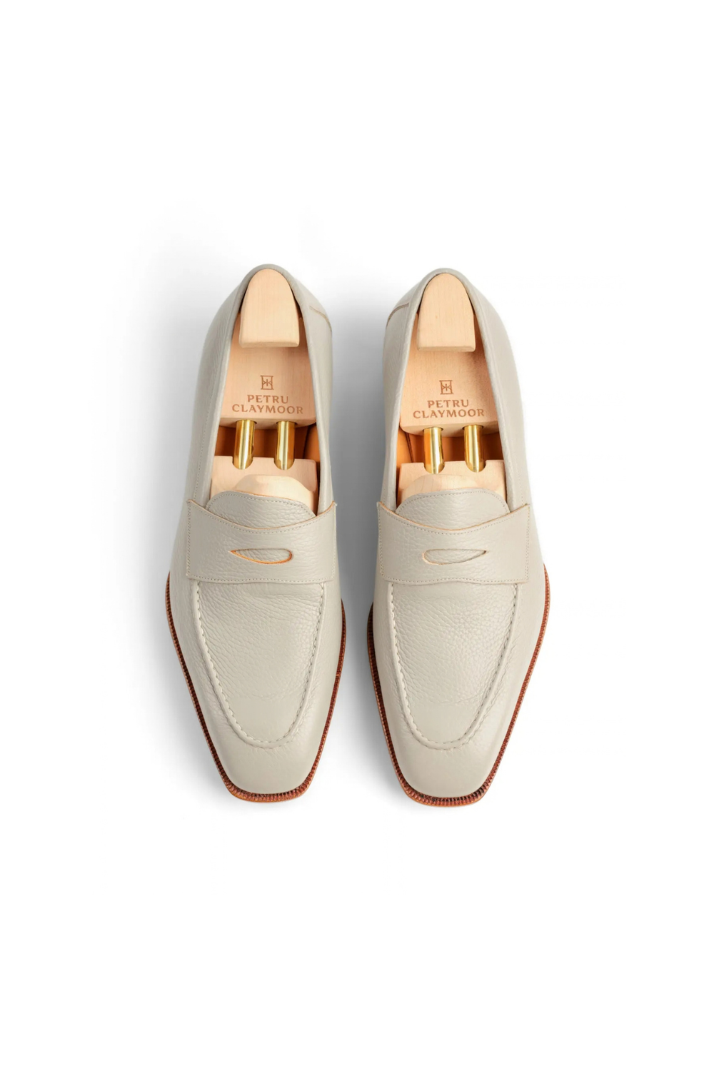 Light gray leather loafers with a stitched detail and wooden shoe trees inside.