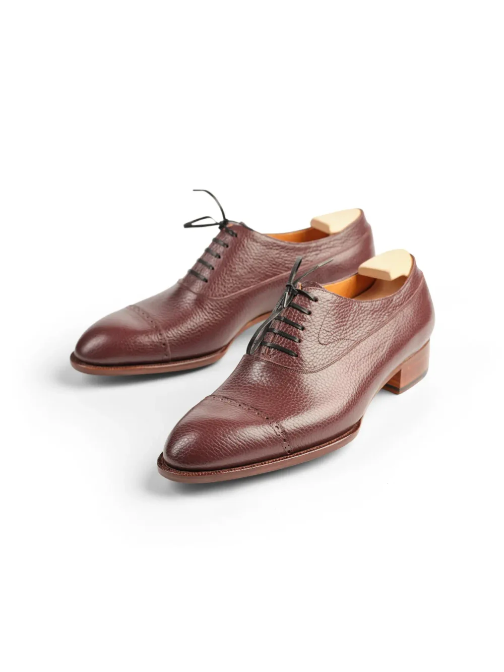 Burgundy leather dress shoes with a textured finish and black laces.