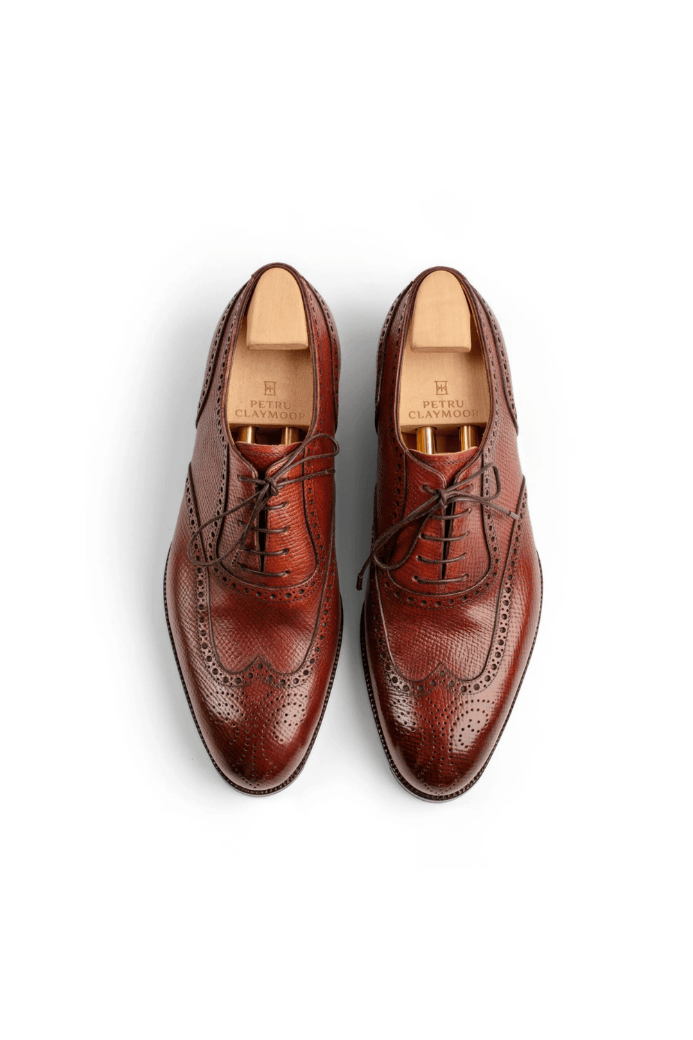 A pair of brown leather brogue shoes featuring intricate perforations and laces.