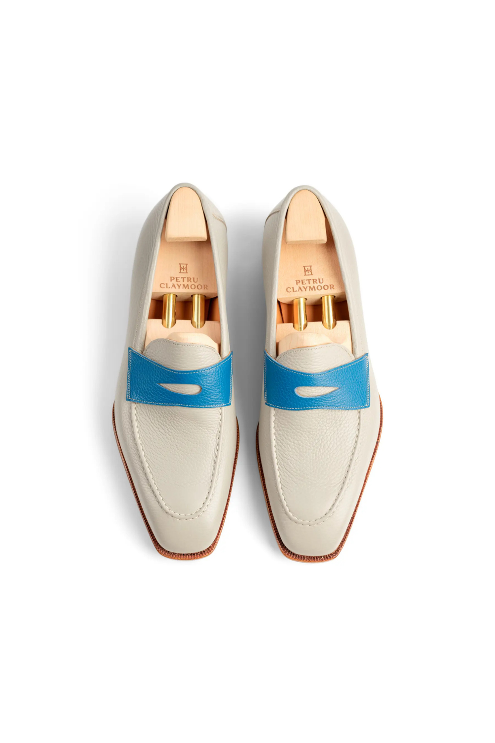A pair of light gray leather loafers with a blue strap and wooden shoe trees inside.