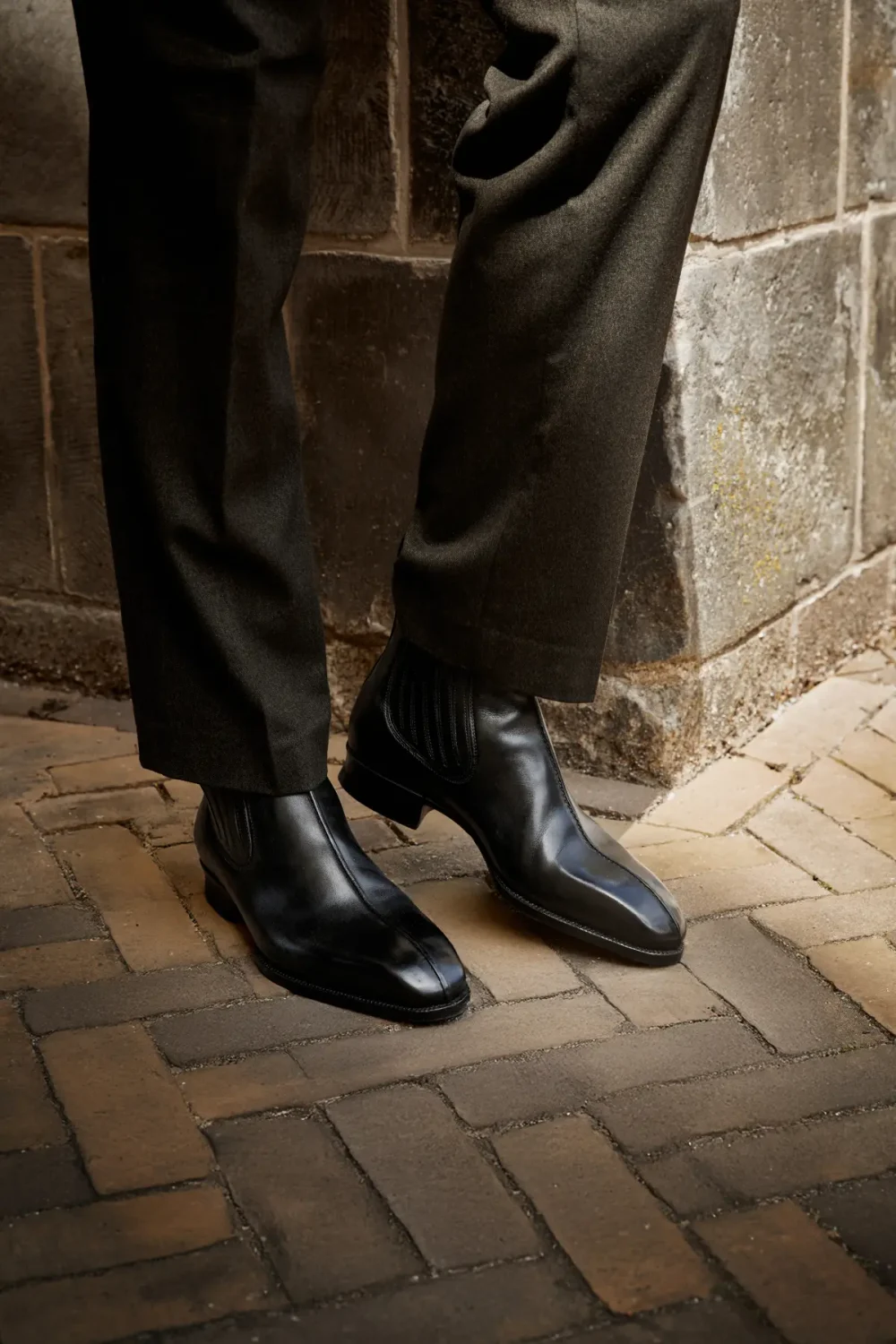 Black leather ankle boots worn with dark trousers.