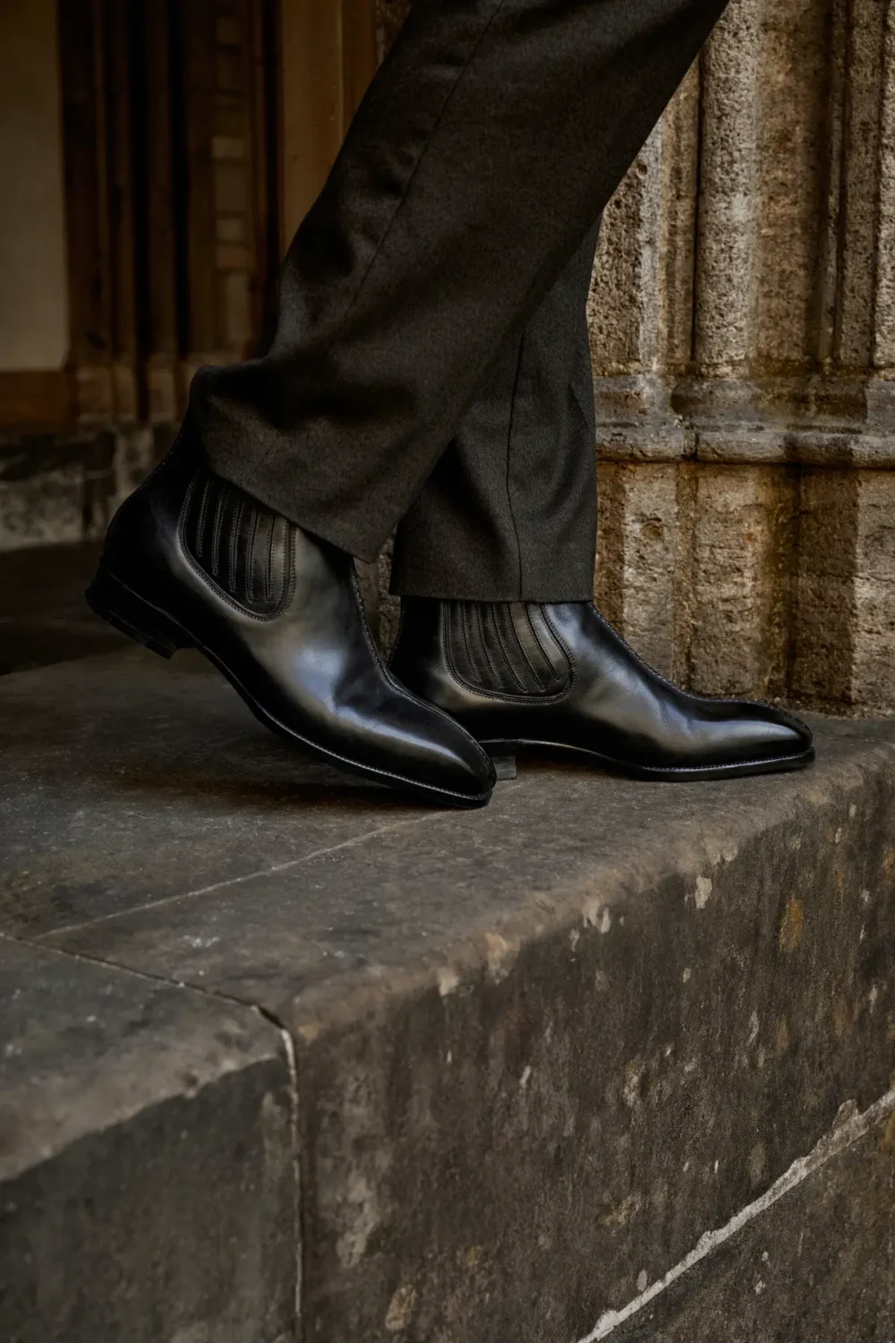 Black leather ankle boots with ribbed detailing, worn with dark trousers.