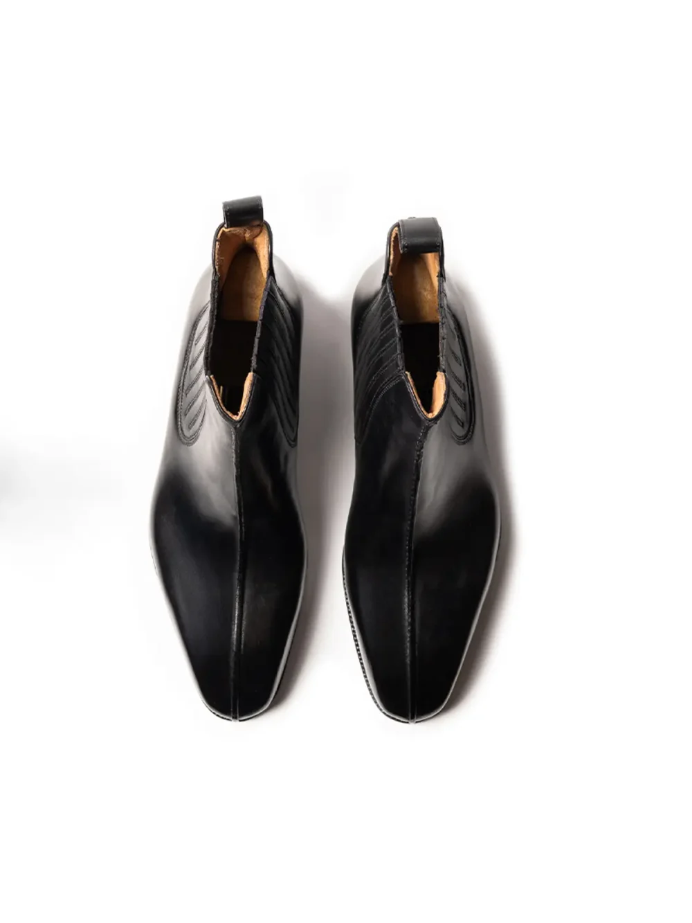 A pair of black leather shoes with a pointed toe and elastic side panels.