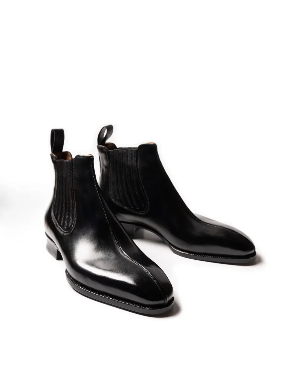 A pair of sleek black leather Chelsea boots with ribbed elastic panels.