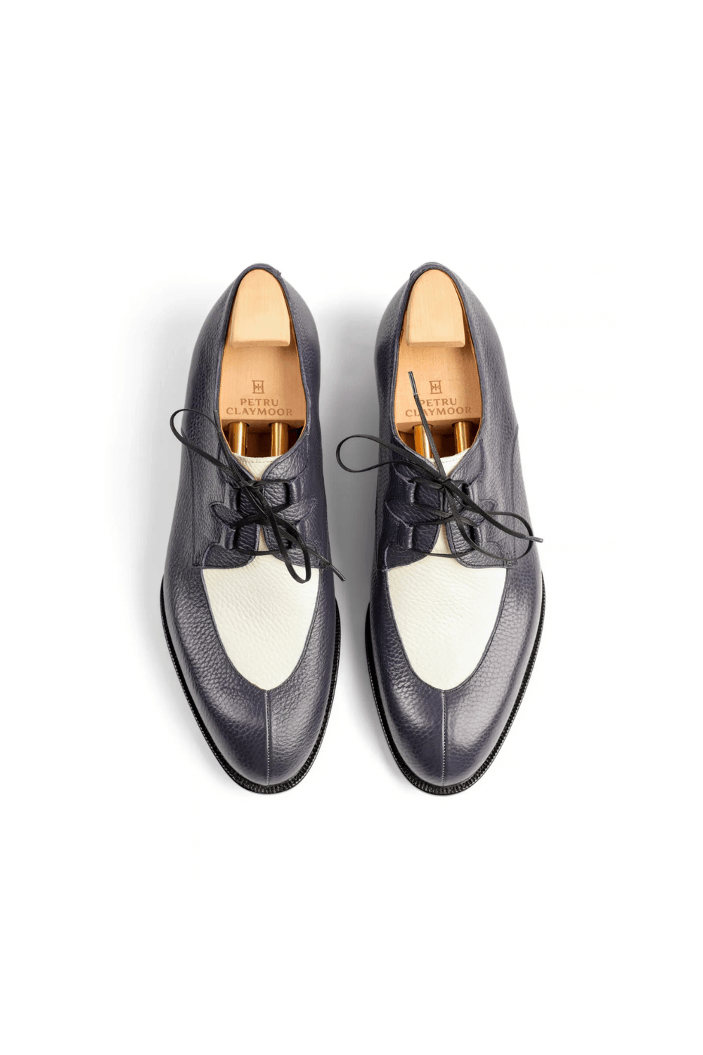 Two pairs of navy blue leather shoes with white accents and black laces, featuring a wooden insole that displays the brand name "Petru Claymoor."