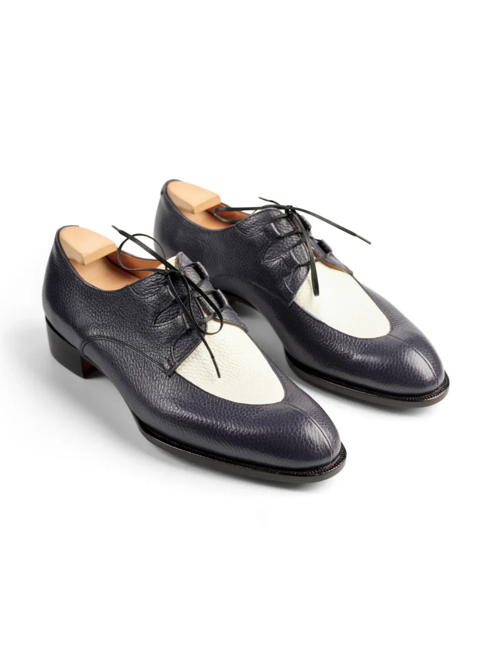 A pair of navy leather shoes with a white leather toe cap and black laces.