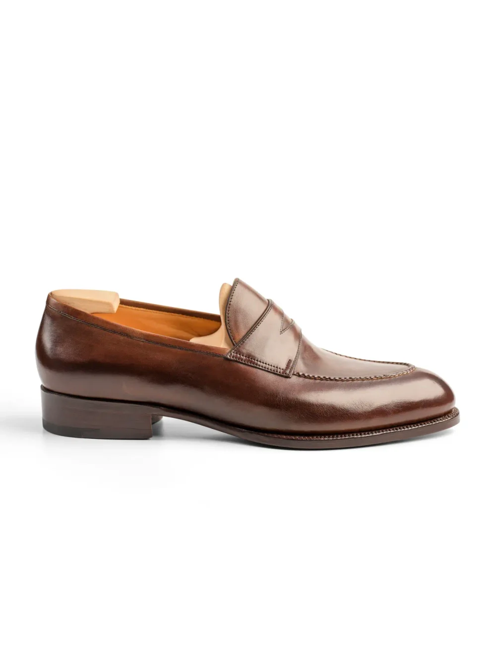 A brown leather loafer shoe with a stitched design and a low heel.