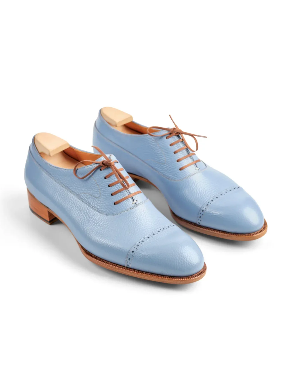 Light blue leather dress shoes with brown laces and a wooden heel.