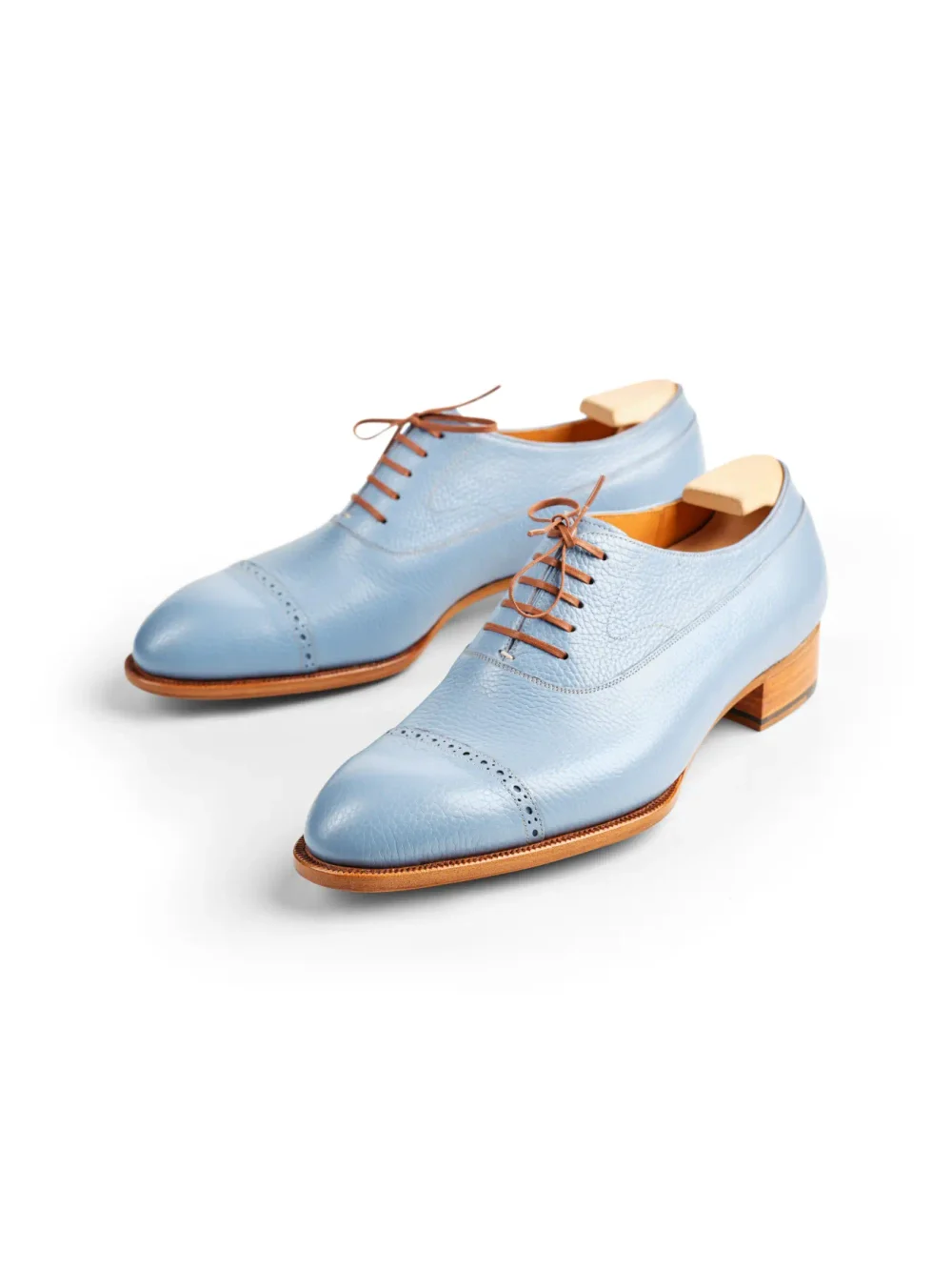 Light blue leather dress shoes with brown laces and a wooden heel.