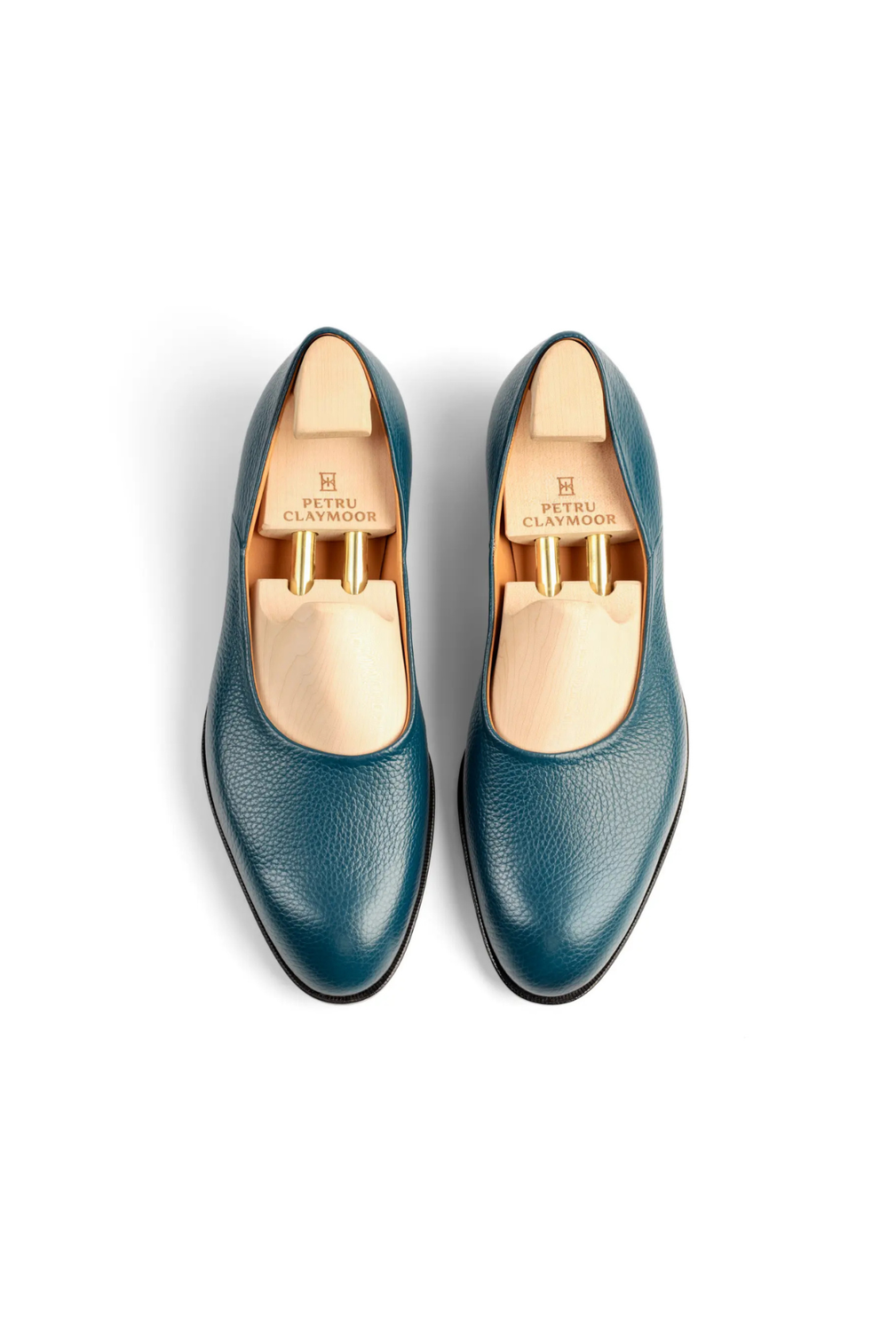 A pair of teal leather shoes with wooden shoe trees inside.