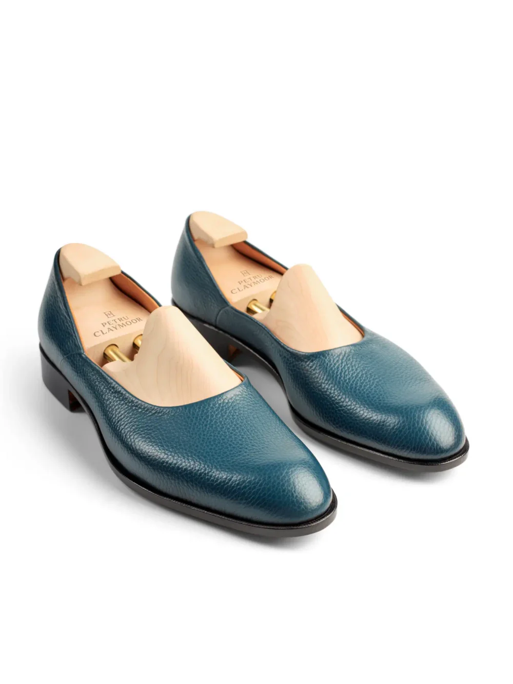 Two teal leather shoes with wooden shoe trees inside.