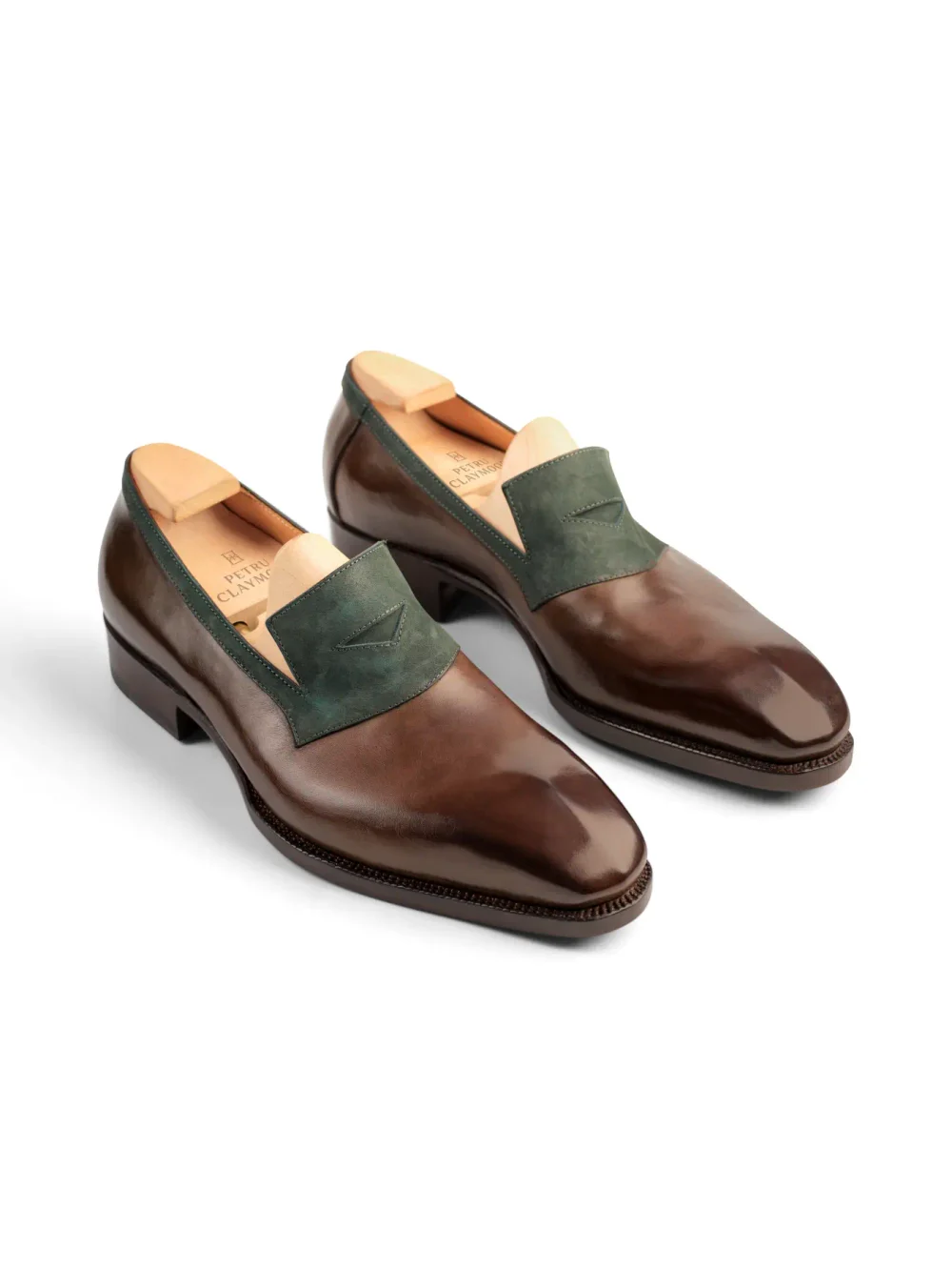 A pair of brown leather shoes with a green suede accent on the vamp.